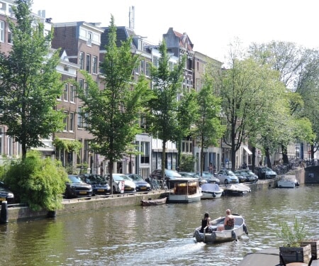 Twee personen die een met een bootje varen op een gracht in Amsterdam.